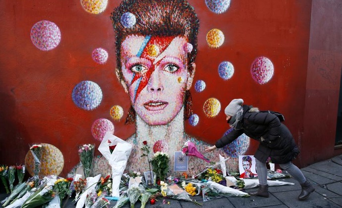 A woman leaves a bouquet at a mural of David Bowie in Brixton, south London, January 11, 2016. Photo: Reuters