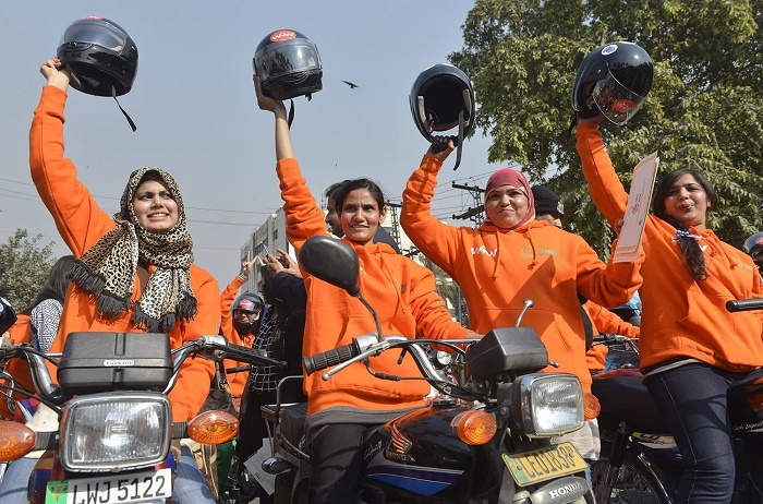 Women participants of Women on Wheels (WOW) raise their helmets at the start of a rally launching the Women on Wheels campaign in Lahore.─AFP