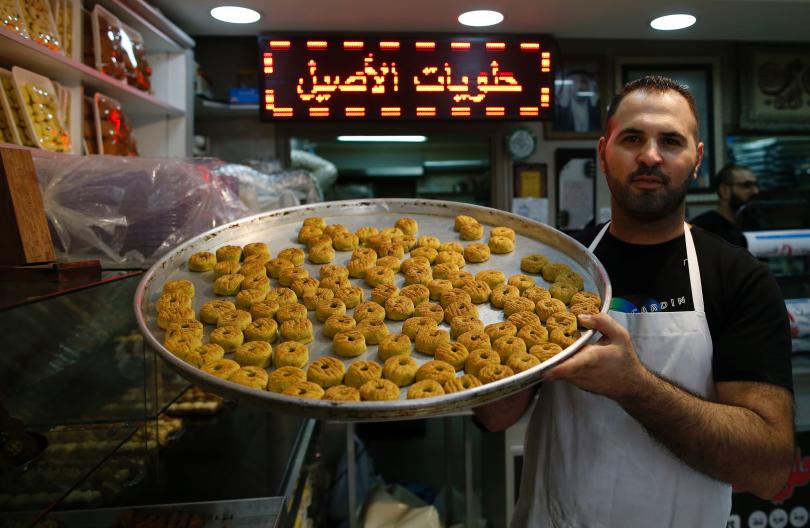 A Palestinian man shows traditional date-filled cookies at a bakery in Jerusalem's Old City on July 5, 2016, ahead of Eid-ul-Fitr. Photo: Ahmad Gharabali/AFP/Getty
