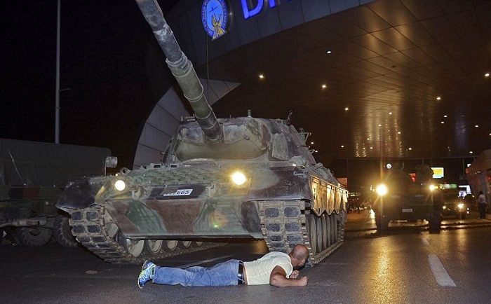 A man lays in front of a tank in the entrance to Istanbul's Ataturk airport, early Saturday, July 16, 2016. Photo: Ismail Coskun/IHA via AP