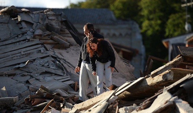 Residents stand among damaged buildings after a strong earthquake hit Amatrice on Wednesday. Central Italy was struck by a powerful, 6.2-magnitude earthquake in the early morning. Photo: Filippo Monteforte/AFP/Getty Images