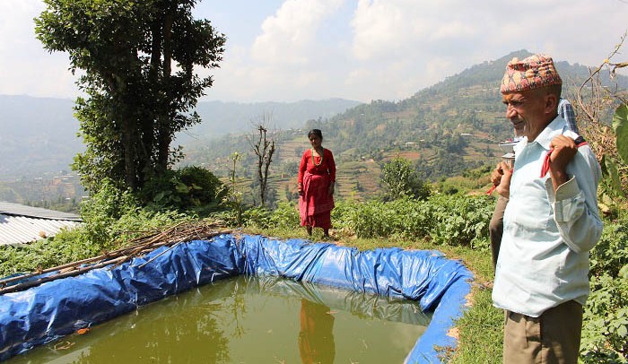 Geeta Kuikel and her husband standing near their plastic pond, commonly used for water conservation in Nepal's villages. Photo: Sana Jamal