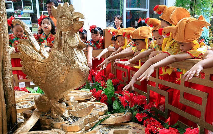 Filipino-Chinese students with rooster hats gesture after tossing a coin in front of a Prosperity Tree display, which is believed to bring good luck and fortune, on Lunar New Year celebrations at the Lucky Chinatown mall in Binondo city, metro Manila, Philippines January 26, 2017. Photo: Romeo Ranoco/Reuters