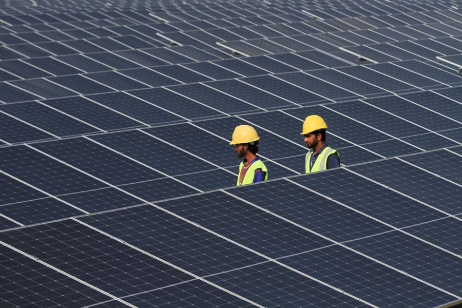 Technicians walk between solar panels